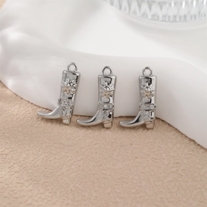 Vue détaillée des pendentifs bottes de cowboy argentées avec motifs soleil et strass