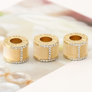 Three gold beauty engraved cylinders with cream enamel and white rhinestones