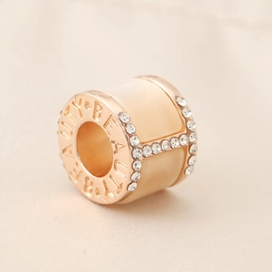 Macro detail of rose gold charm with H letter diamond pavé and Beauty engraving