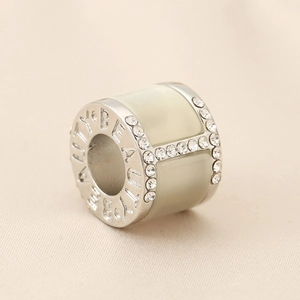 Macro view of silver cylinder charm with diamond H letter and BEAUTY engraving