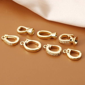 Gold plated cubic zirconia pinch bails for DIY jewelry making on leather background