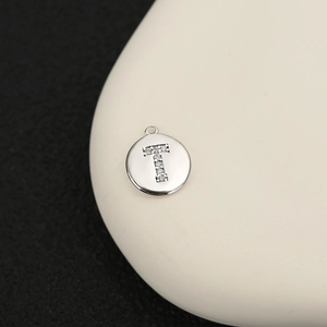 Detalle macro del colgante redondo de plata con una letra T engastada con pavé de cristal