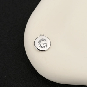 Primer plano de un colgante de letra G plateado con circonitas transparentes micro-pavé