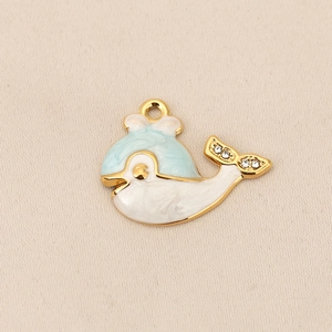 Détail du pendentif baleine avec émail bleu et cristaux brillants sur tissu beige