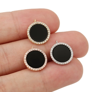 Detail of round 18K gold plated pendants with black enamel and sparkling zircon inlay