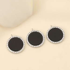 Close-up of three circular black enamel pendants with sparkling micro-pave zircon borders