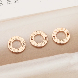 Tre perle donut placcate oro 18K con incisione BEAUTY su uno sfondo di seta lucida