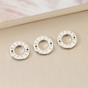 Vista macro di perle tonde in argento con incisione Beauty per creare gioielli
