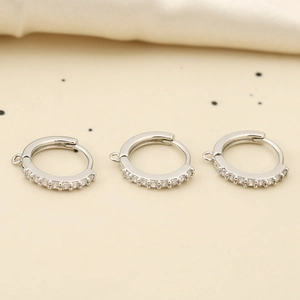 Macro-opname van drie zilveren oorringen met zirkonia en kleine ophanglussen voor DIY-sieraden