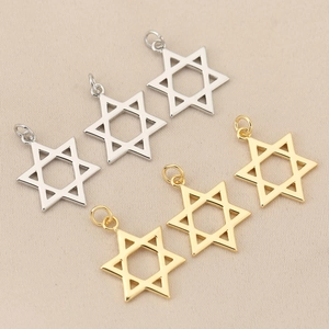 Detailed view of polished gold and silver hexagram star pendants on fabric background