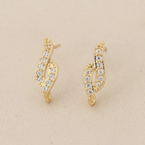 Détail macro de boucles d'oreilles ondulées plaquées or 18K avec zircons brillants