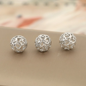 Detailed macro view of three silver hollow heart-shaped metal beads for DIY jewelry making