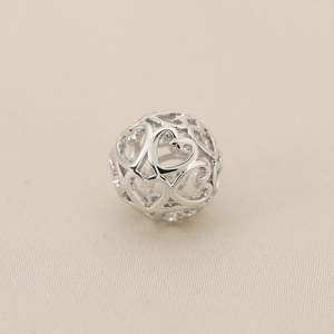 Macro shot of silver hollow ball bead with overlapping heart patterns for DIY jewelry