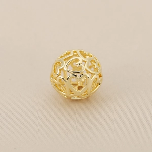 Detailed close-up of a 18k gold plated hollow heart patterned round spacer bead for DIY jewelry