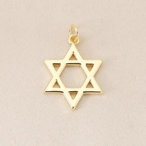 Detailed view of polished 18K gold-plated hexagram star pendant on fabric