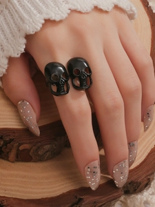 Anillos góticos de calavera negra en la mano del modelo sobre un fondo de madera