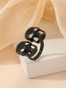Primer plano de anillo gótico negro con doble calavera sobre fondo de seda elegante