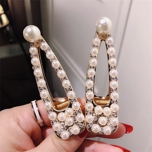Detailansicht goldener Haarklammern mit eleganten Perlen und glänzenden Strasssteinen