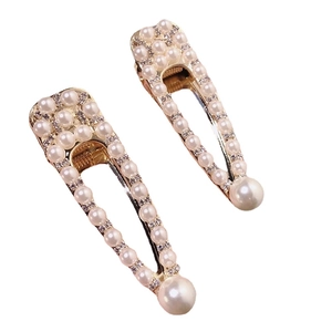 Elegant gold hair clips with white imitation pearls and rhinestones on a white background