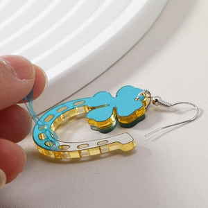 Détail montrant le retrait du film protecteur des boucles d'oreilles trèfle