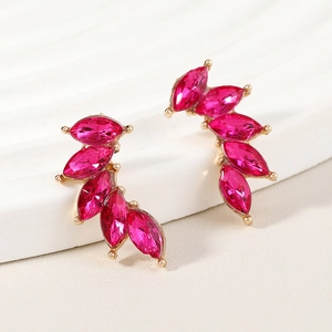 Macro detail of gold-plated alloy leaf earrings with rose red marquise-cut crystals
