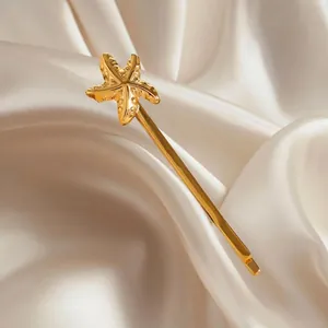 Goldene Seestern-Haarklammer mit Metalltextur auf elegantem beigen Satin-Hintergrund