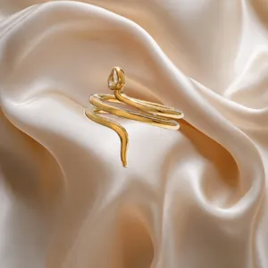 Elegante anillo de serpiente dorado con circonita de lágrima sobre seda de lujo