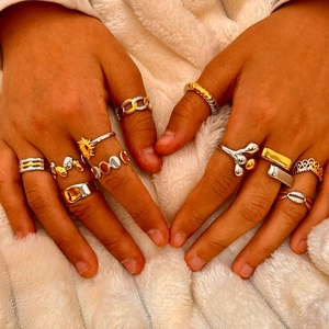 Primer plano de anillos apilables bicolor oro y plata con diseños de sol y geométricos