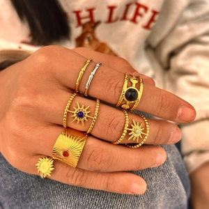 Dettaglio di anelli bohémien placcati in oro con gemme colorate sulla mano della modella