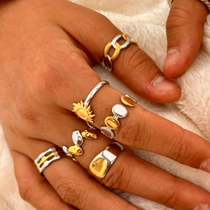 Primer plano de anillos apilables de oro 18K y plata sobre fondo de piel sintética