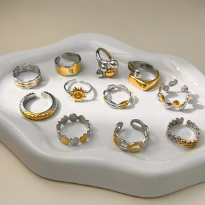 Set de 11 anillos de acero inoxidable en oro y plata sobre un plato cerámico ondulado
