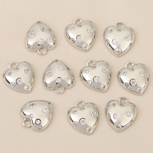 Detailed view of ten heart-shaped silver pendants set with sparkling zircon stones