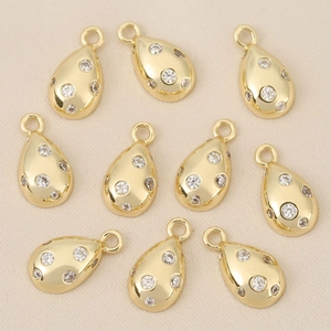 Detailed macro view of 10 gold-plated teardrop charms with zircon inlays for DIY jewelry