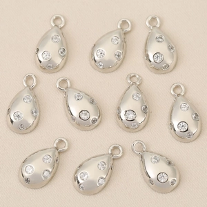 Macro view of ten water-drop zircon pendants with 18k gold plating on beige background