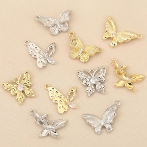 Détail de pendentifs papillons dorés et argentés avec incrustations de zircons étincelants