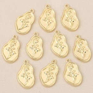 Makroansicht von zehn goldfarbenen Maiglöckchen-Relief-Anhängern für die DIY-Schmuckherstellung