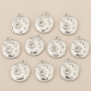 Detail view of 18k gold plated sun and moon charms with zircon insets on beige fabric