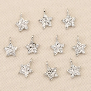 Macro shot of ten star-shaped silver pendants with micro-pave zircons for DIY jewelry