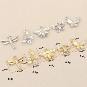 Detailed view of small dragonfly and bee charms with white cubic zirconia in gold and silver