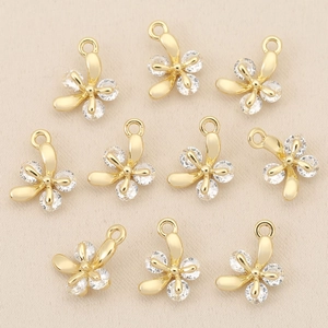 Close-up of 10 gold-plated flower pendants with inlaid crystals for DIY jewelry making