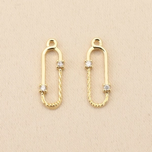 Detailed macro view of 18k gold plated safety pin pendant with zircon and spiral twist design