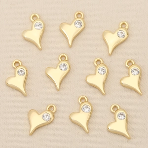 Close-up of gold heart pendants with inset zircon stones for DIY jewelry making