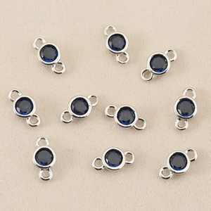 Macro detail of ten silver-plated double-loop connectors with deep blue round zircons
