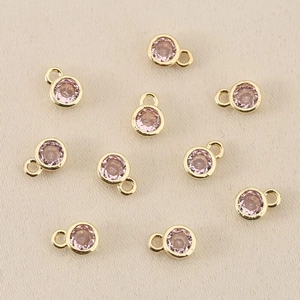 Makroaufnahme von zehn runden rosa Edelsteinanhängern mit polierter 18k Goldbeschichtung