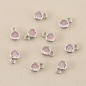 Makroaufnahme von 10 rosa Zirkonia-Anhängern in Silberfassung für DIY-Schmuckherstellung