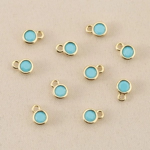 Detailansicht von zehn 18k vergoldeten runden Anhängern mit hellblauem Zirkon für DIY Schmuck