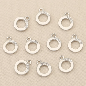 Detailed view of silver plated pendants with cubic zirconia inlay on textured fabric