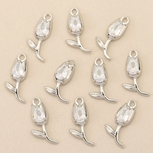 Detailed close-up of 10 tulip pendants with cubic zirconia inlay on beige fabric
