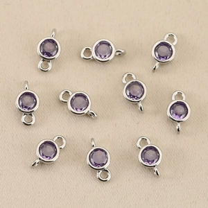 Macro detail of round purple birthstone connectors with 18k gold plating for jewelry DIY