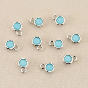 Detailansicht von zehn hellblauen runden Geburtsstein-Anhängern für DIY-Schmuck
